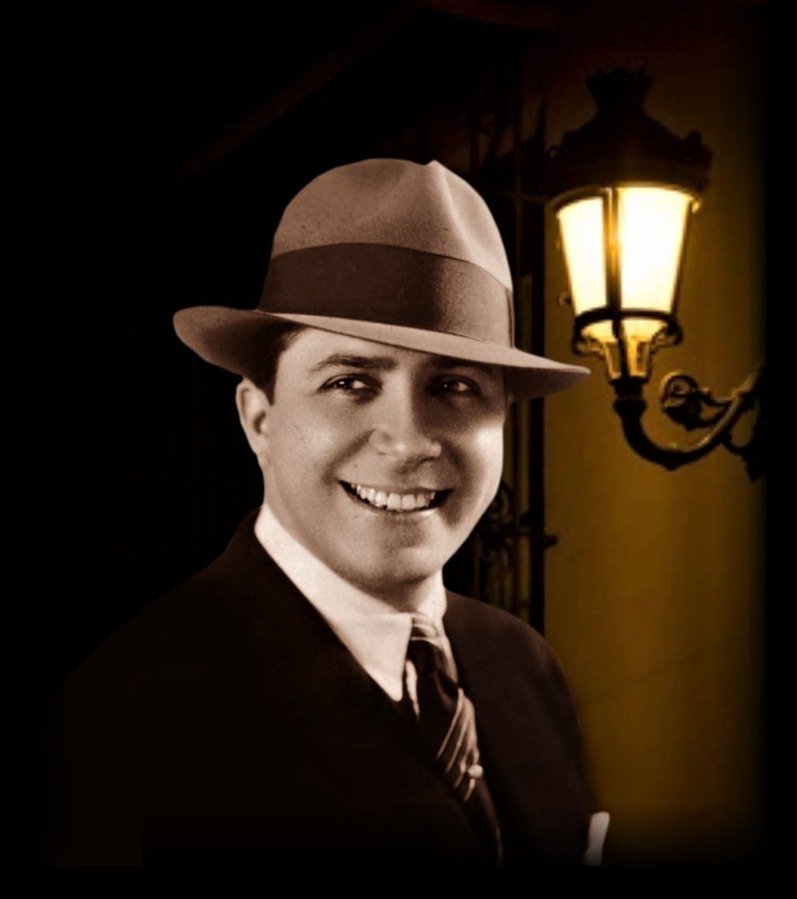 Carlos Gardel in a hat beside a street lamp